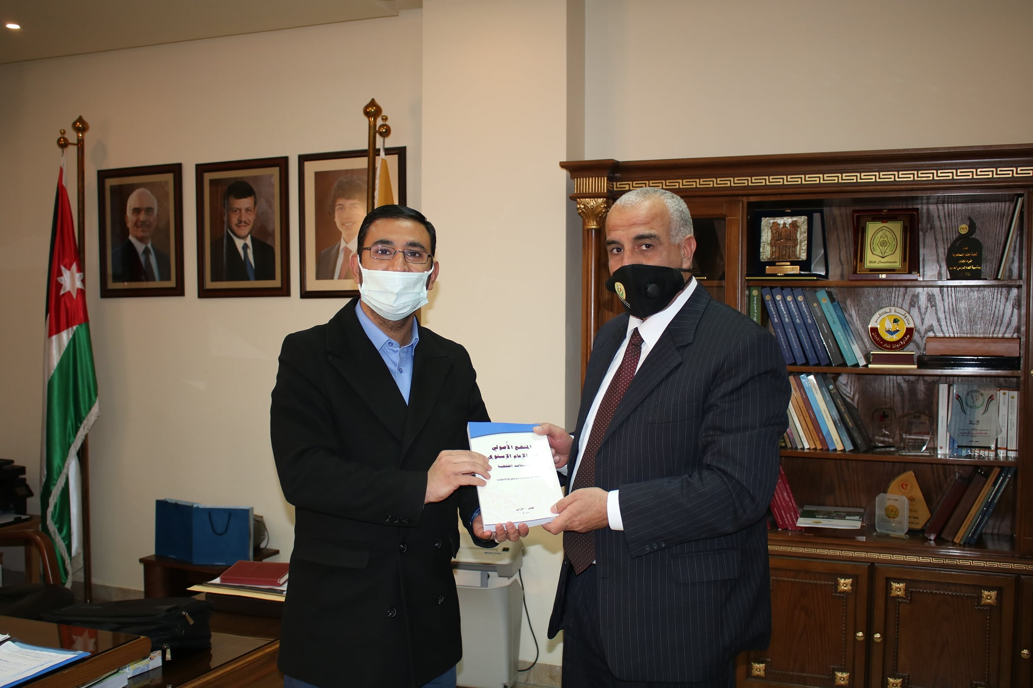 Researcher Laith Al-Azab gives the university president a copy of his book